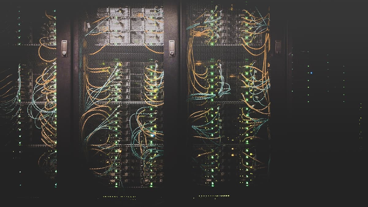 Data centre aisle lined with server racks and structured cabling under status indicator lights