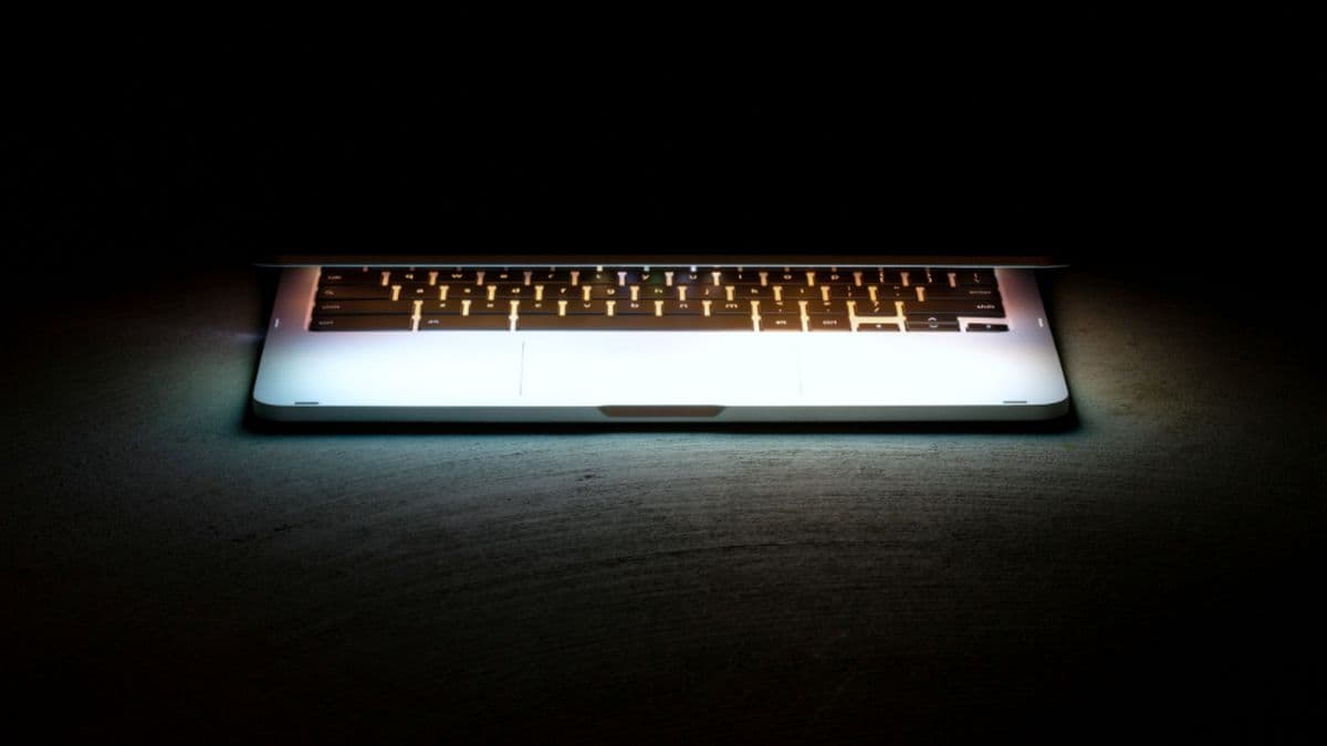 Open laptop glowing in a darkened room, running a cloud-hosted application