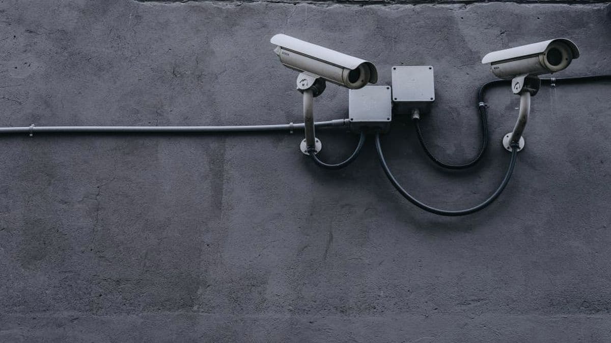 Pair of bullet surveillance cameras mounted on a grey concrete wall