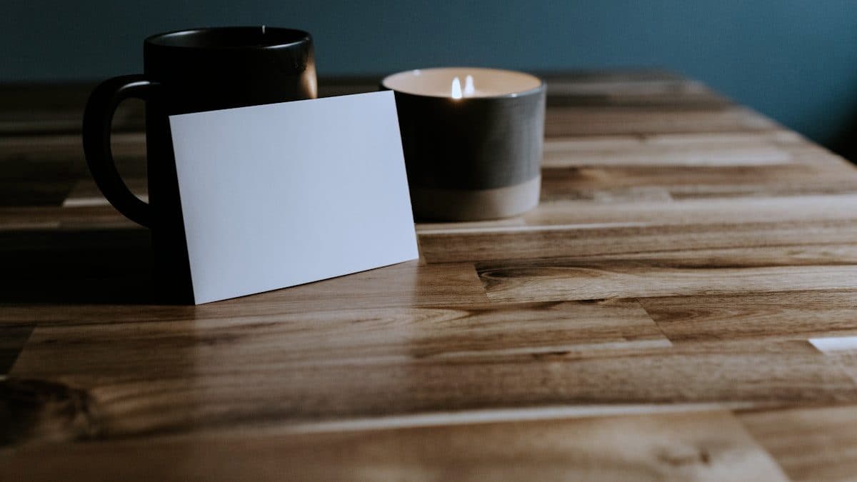 Blank card standing against a mug on a wooden table, ready for brand application