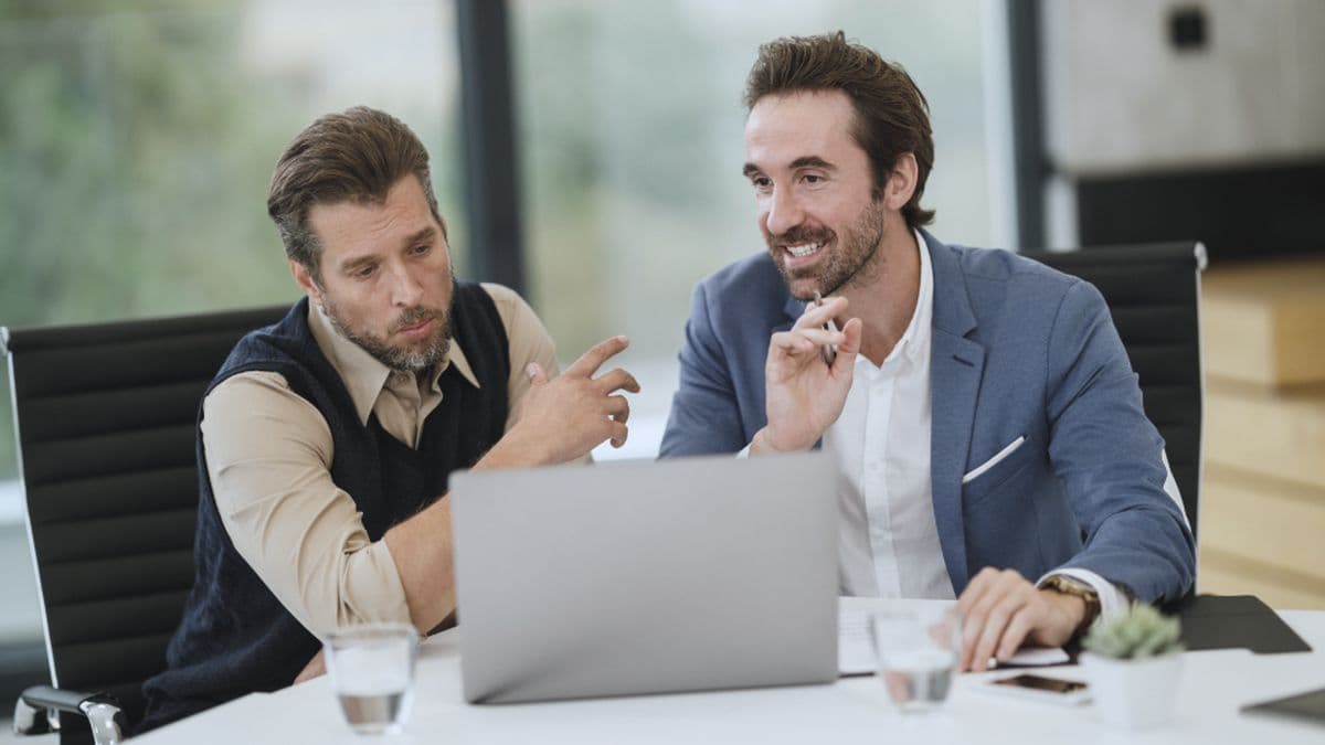 Two advisors weighing options together over a laptop in a bright meeting room
