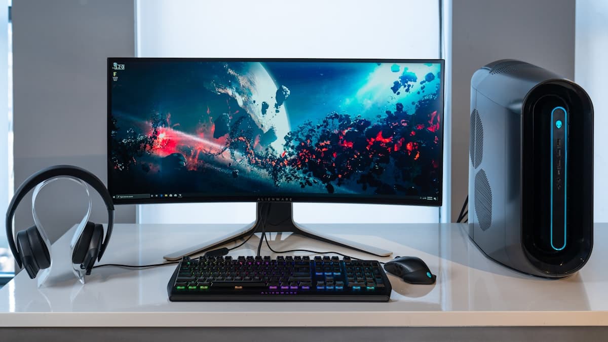 Desk setup with a widescreen monitor, desktop tower, keyboard, mouse, and headset