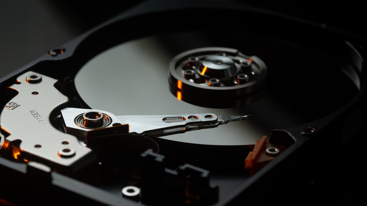 Enterprise hard drive with its platter and read head exposed, lit against a dark background