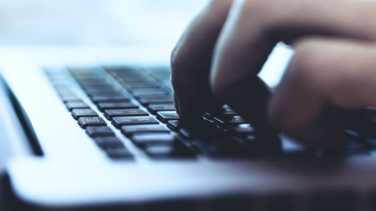 Hands typing on a laptop keyboard in cool daylight