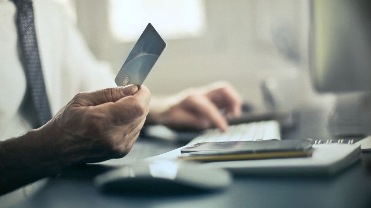 Person holding a payment card while checking out at a desktop computer